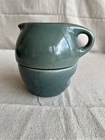 Stacked view of cream pitcher resting on sugar bowl base showing teal glaze and rounded forms