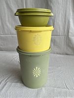 Stacked view of three vintage Tupperware canisters showing size and floral designs on sides