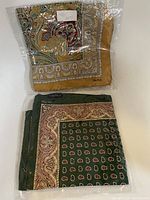 Two folded Nautica scarves in sealed plastic packaging, showing paisley and ornamental designs in various colors.