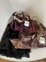 Three sequined apparel items including black tank top, gold/purple reversible sequin pouch, and brown sequin pouch with tags.