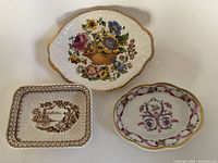 Top view showing three decorative ceramic dishes with various floral and scenic designs.