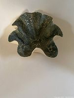 Top view of signed art wave pottery bowl with textured scale-like pattern and wavy edge