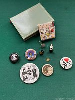 Overview of vintage button pins and Snoopy collectible item alongside a small box on green background