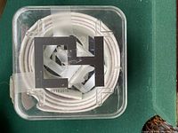 Clear plastic box containing a tightly coiled white belt with Thelwell logo visible on the buckle.