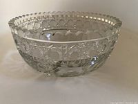 Side angle view of clear round cut crystal bowl showing detailed cut pattern and scalloped rim.