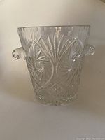 Front view of the clear crystal ice bucket showing etched patterns and side handle.