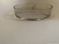 Side view of the round glass candy dish showing the clear glass, etched starburst design, and height of the dish.