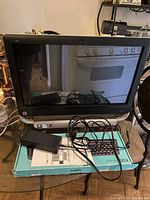 HP touchscreen all-in-one computer with power adapter and cables on a table