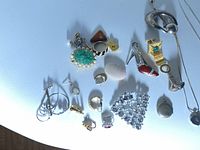 Various pins, brooches, earrings, and a shell pendant arranged on a light surface showing mixed costume and vintage jewelry pieces.