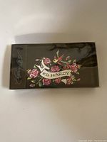 Wallet in original Ed Hardy branded box showing design featuring roses, swallow bird, and brand name banner.