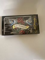 Ed Hardy wallet in original closed box displaying floral and bird graphic with snakeskin background.