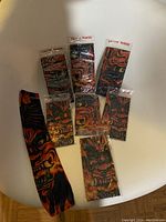 Full set of 7 tattoo sleeves in packaging arranged on white surface showing various fiery and demonic graphic designs