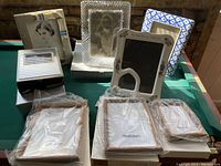 Ten assorted photo frames arranged on a table, some containing vintage black and white photos, others are empty or still in original plastic wrapping.