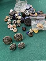 Vintage Air Force buttons with eagle shield and 13 stars in foreground, assorted buttons behind on green background.