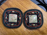 Front view of pair of square-shaped vintage earrings showing the beadwork and central stone.
