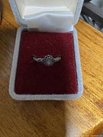 Photo showing vintage silver tone ring with central oval design in red velvet jewel box.