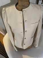 Front view of vintage cream Sasson blazer on dress form showing button closure and round collarless neckline.