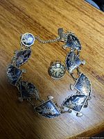 Photo showing the vintage Siam bracelet made of linked fan-shaped enamel panels with gold-tone details alongside a single matching clip-on earring.