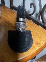 Vintage spoon ring displayed on a black ring stand showing front design of cherub face.