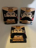 Three packages of Western Moustaches showing black thick fake moustaches on illustrated cowboy face cards.