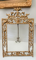 Full front view of ornate gilt metal frame showing overall filigree design and stand