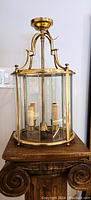Full view of lantern hanging light showing brass frame, glass enclosure, and ceiling mounting canopy.