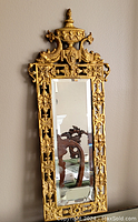 Full upright view of the ornate brass framed mirror with visible detailed fish motifs and urn finial.