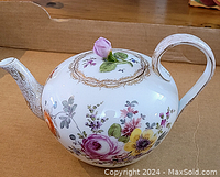 Full side view of floral decorated porcelain teapot with rose lid showing shape and spout detail