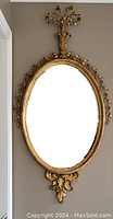 Full view of oval giltwood mirror hanging on wall