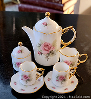 Full view of the miniature tea set including teapot, sugar bowl, two cups, and two saucers featuring pink rose floral pattern and gold trim.