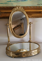 Front view of entire tabletop swivel mirror showing oval frame, support columns, and mirrored base