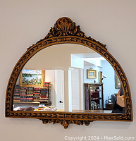 Front view of giltwood wall mirror showing the full arched shape, shell detail at top, and carved border pattern.