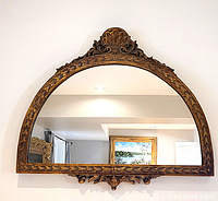 Front view of giltwood half-round wall mirror showing detailed frame work and clear reflective glass.