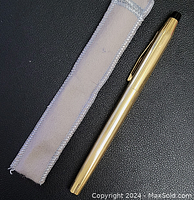 Pen with cap on alongside fabric sleeve on black background