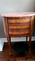 Front view of demilune side table showing three drawers, wood veneer inlay and cabriole legs