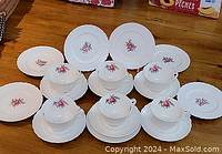 Overhead view of five teacup and saucer sets with matching plates arranged on table