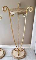 Full view of the stand showing the faux marble top and base, and the gold metal V-shaped frame with scroll accents.