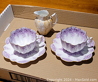 Wide view of two purple transferware teacups with matching saucers and a gilt-transferware creamer jug