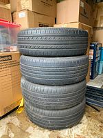 Stack of four used tires in storage area with cardboard boxes.