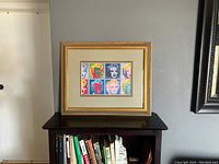 Frontal image of framed colorful Marilyn Monroe print on a bookshelf