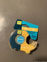 Photo of new Seal-It 2 Side It double-sided tape in original packaging, blue and yellow dispenser visible with labeling and tape size info.