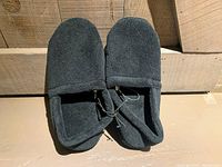 Top view of the black slippers showing the soft fabric upper surfaces and attached tags.
