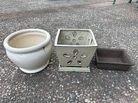 Three garden pots side by side on a stone floor showing different shapes and colors.