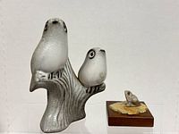 Front view showing two greyish-white birds perched on a textured branch figurine and small frog on lily pad figurine in front of it.
