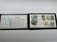Photo showing the stamps mounted inside an open black portfolio with the cranes and postmark visible.