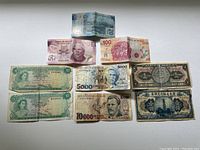 Photo showing a group of nine foreign paper currency bills arranged on a flat surface. Bills include currency from Mexico, Zimbabwe and China.