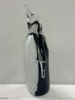 Side view of glass penguin showing the clear head, black and white body, and the wing extending from the side.
