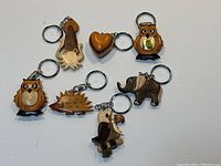 Six wood keychains: owl, squid, heart, porcupine, elephant, toucan, all with metal key rings