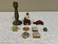 Photo showing full group of mini trinket boxes and animal figures on white patterned cloth.