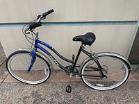 Photo of a blue ladies Huffy bike showing full side profile with black seat and handle grips. Bike has silver fenders on front and rear wheels and appears weather distressed.